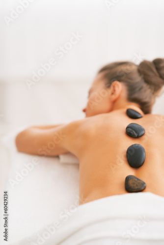 Фотография Young woman receiving hot stone massage. rear view