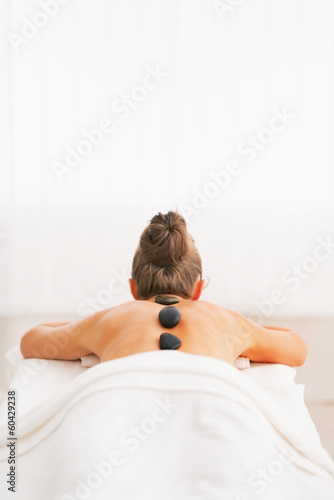 Young woman receiving hot stone massage. rear view