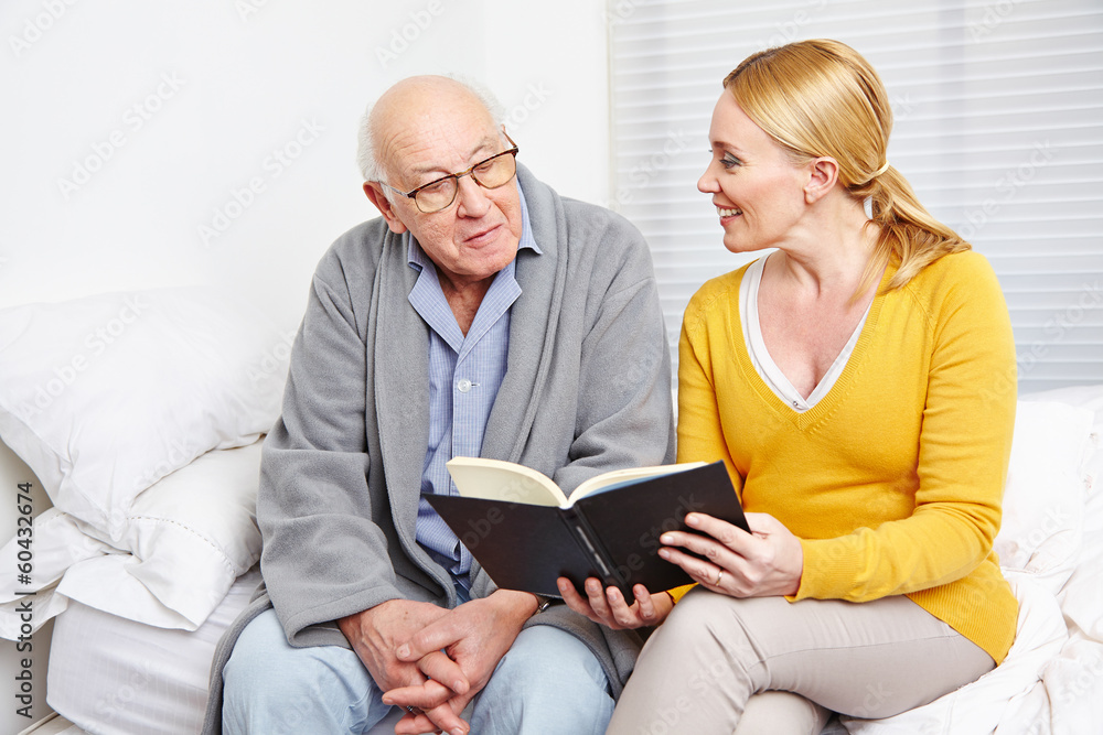 Frau liest altem Mann ein Buch vor