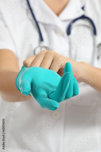 Close up of a female doctor putting a green latex gloves