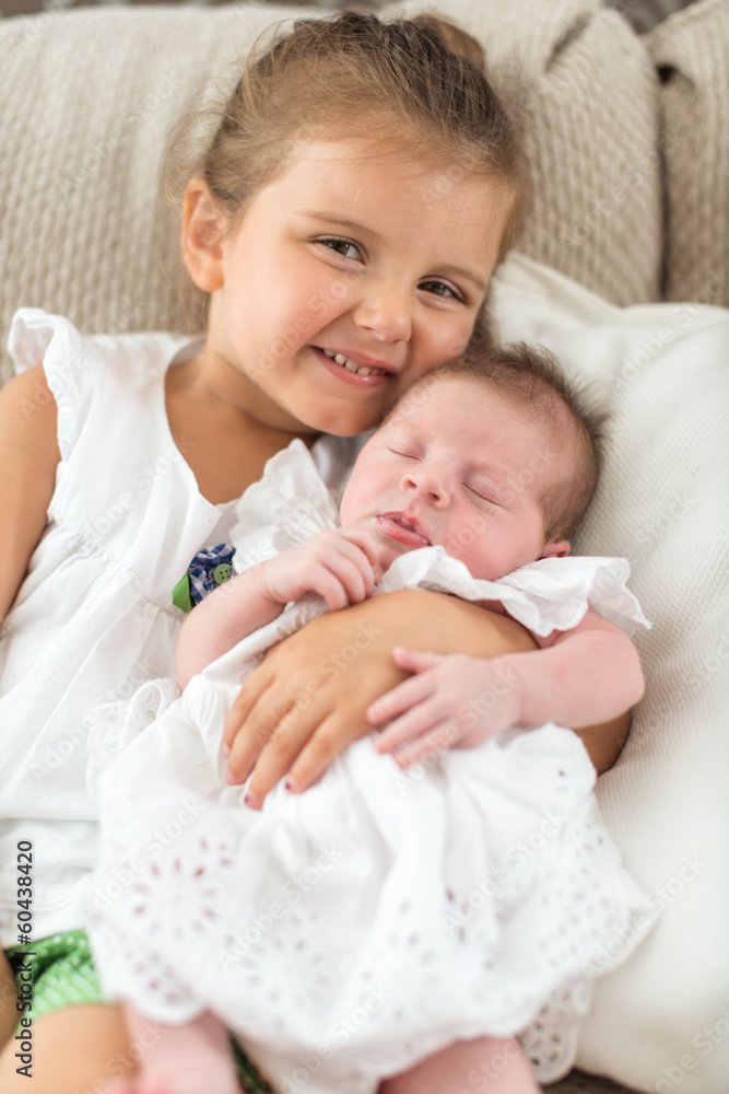 Newborn in a christening dress sleeping in sister Newborn in a christening dress sleeping in sister