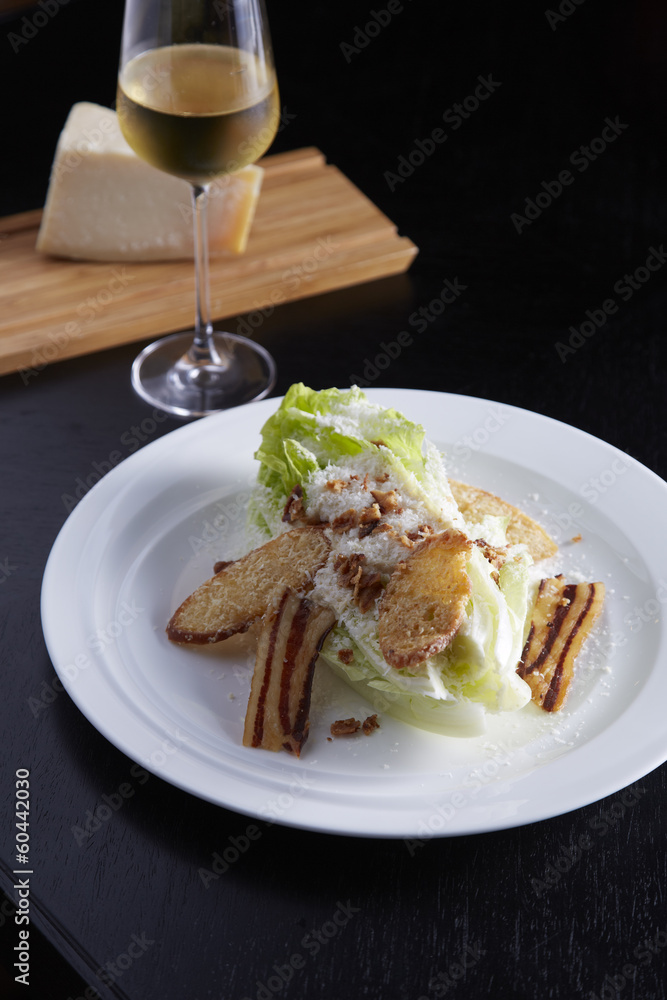Caesar Salad on white plate with wine