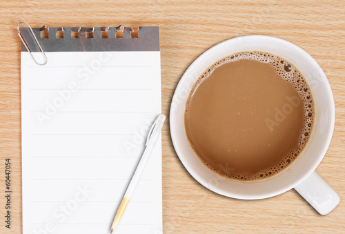 Notebook White cup of hot coffee and Silver pen on Wood table
