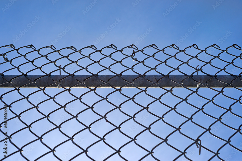 Chain link fence with bar against blue sky Chain link fence with bar against blue sky