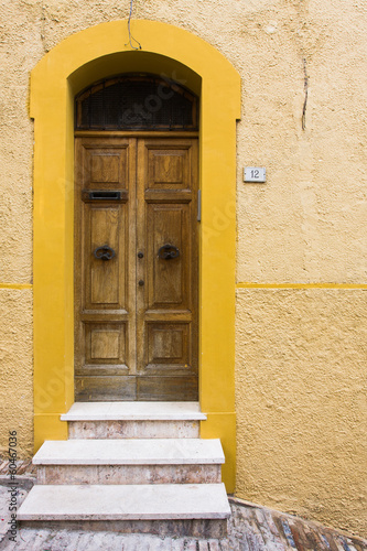 Porta di legno su muro giallo © francescopaoli