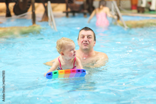 Father teaching his daughter to swim with floating board