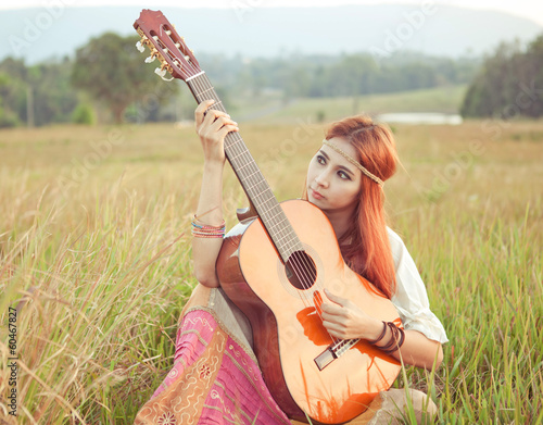 Hippie girl playing guitar on grass