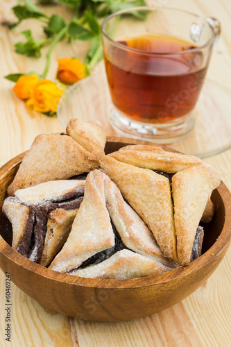 Hamantaschen cookies for Purim with cup of teaon a wooden surfac photo