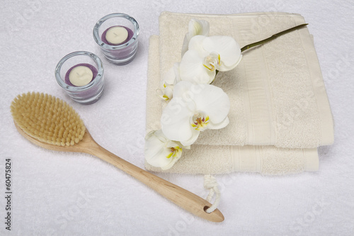 Wellness mit Massagebürste, Handtuch, Kerzen und Orchidee