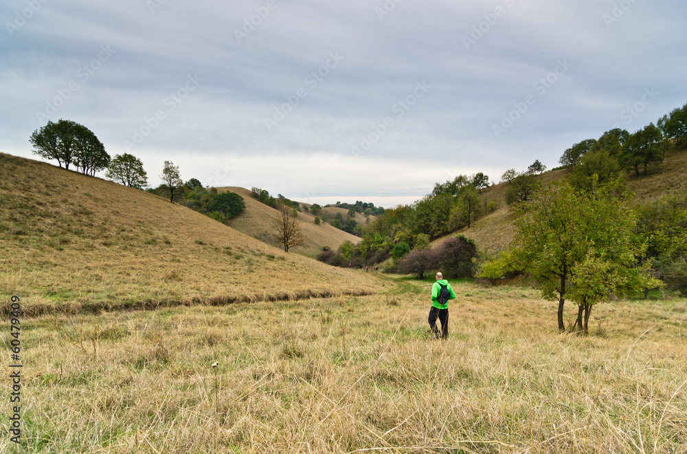 Hiker in a valley between small hills under dark clouds Hiker in a valley between small hills under dark clouds