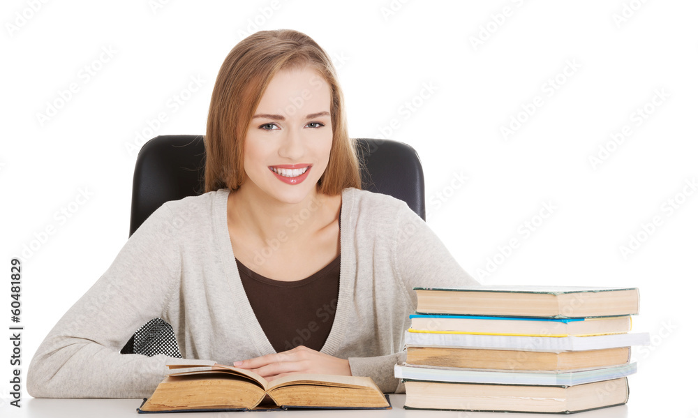 Beautiful student woman sitting by the desk with books and learn Beautiful student woman sitting by the desk with books and learn