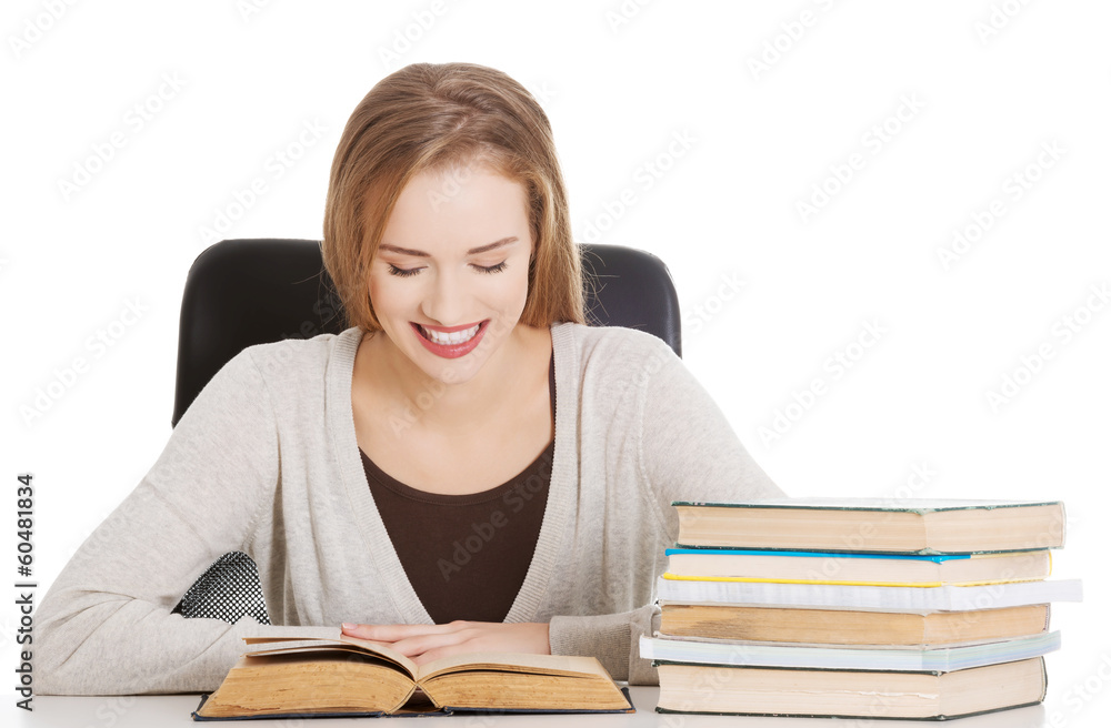 Beautiful student woman sitting by the desk with books and learn Beautiful student woman sitting by the desk with books and learn