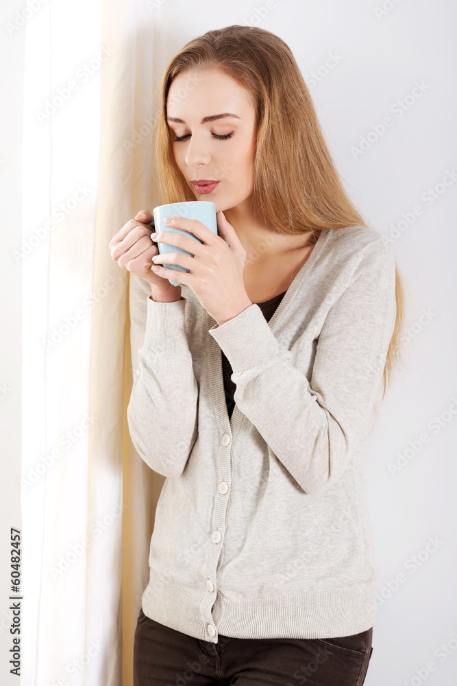 Beautiful casual caucasian woman standing by the window with hot Beautiful casual caucasian woman standing by the window with hot
