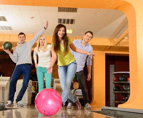 Group of four young smiling people playing bowling