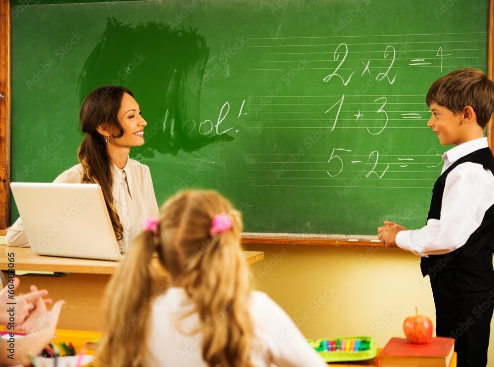 Little schoolboy answering near blackboard in school Little schoolboy answering near blackboard in school