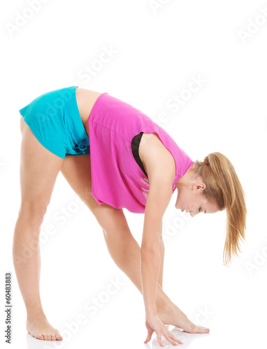 Young caucasian woman is exercising, bending down.