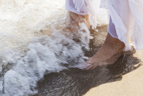 Pictore of feet on a beach and water. photo