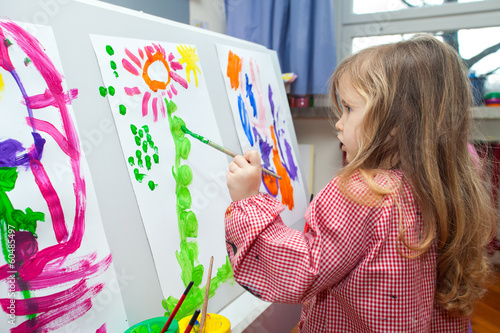 Little girl painting on paper