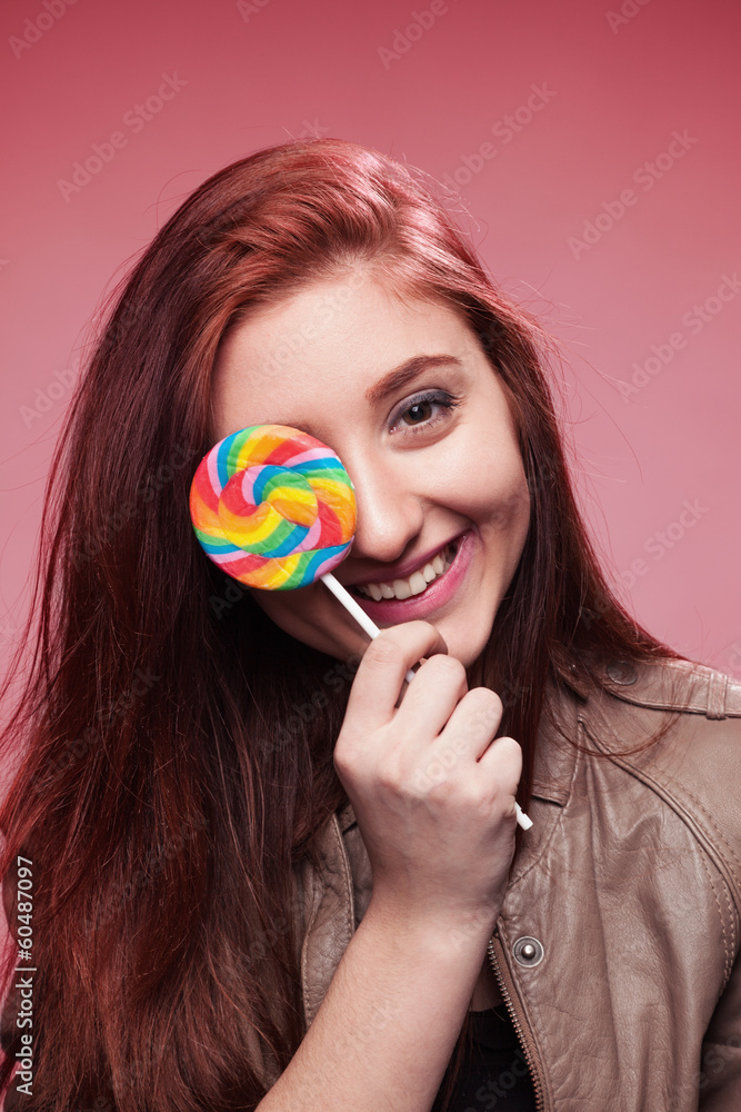 happy young girl with lollipop on a pink