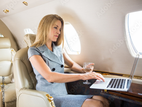 Confident Businesswoman Using Laptop In Private Jet