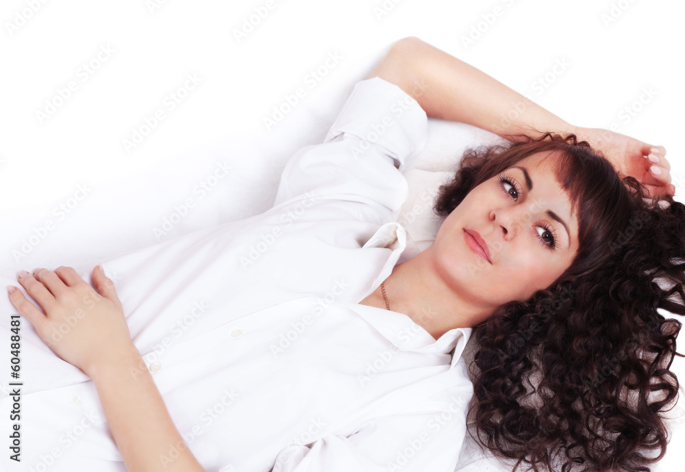 Beautiful young woman in white shirt lying on a bed Beautiful young woman in white shirt lying on a bed