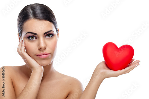 Pensive woman holding red heart