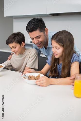 Young kids enjoying breakfast with father in kitchen