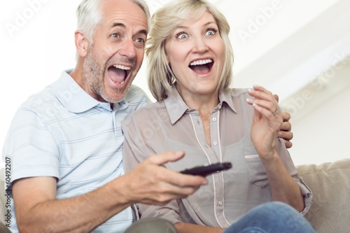 Cheerful couple watching tv on sofa