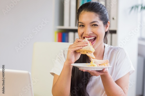 Happy businesswoman eating sandwich