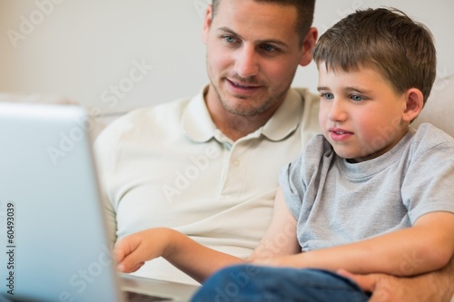 Father assisting boy in using laptop