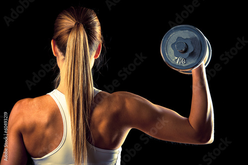 Fitness girl - attractive young woman working out with dumbbells in fitness g...