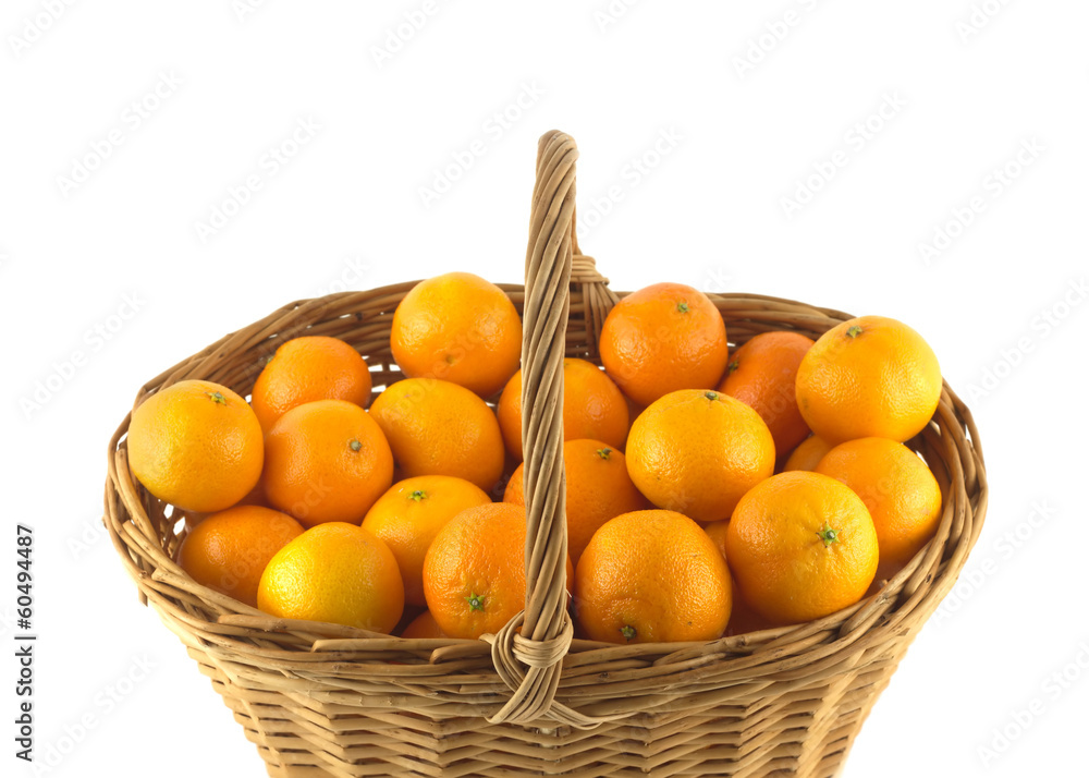 Many orange tangerines in big brown wicker basket isolated