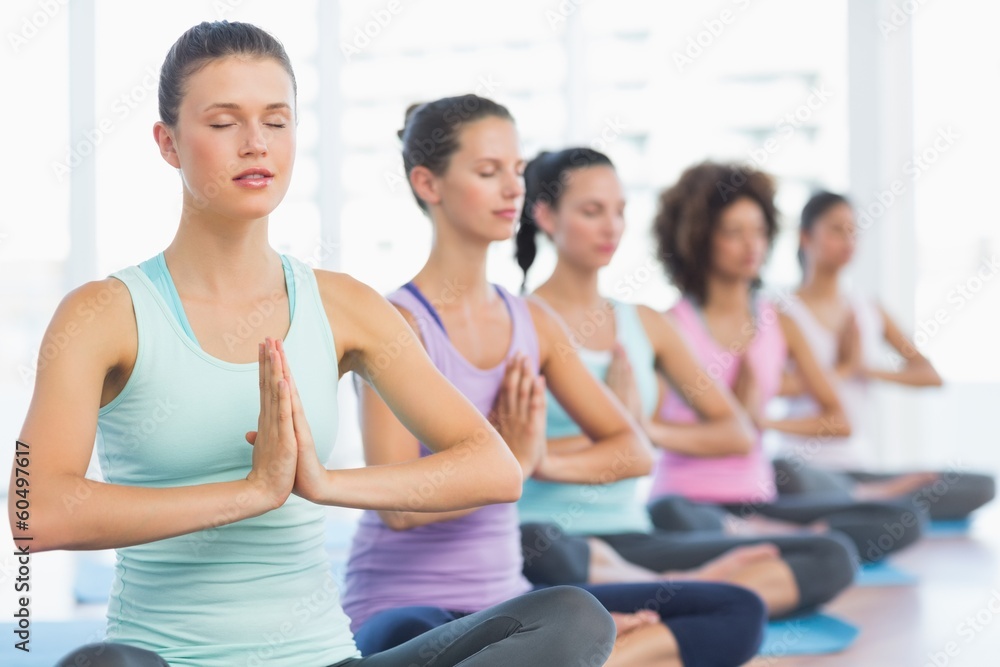 Young sporty women with joined hands sitting in row Young sporty women with joined hands sitting in row