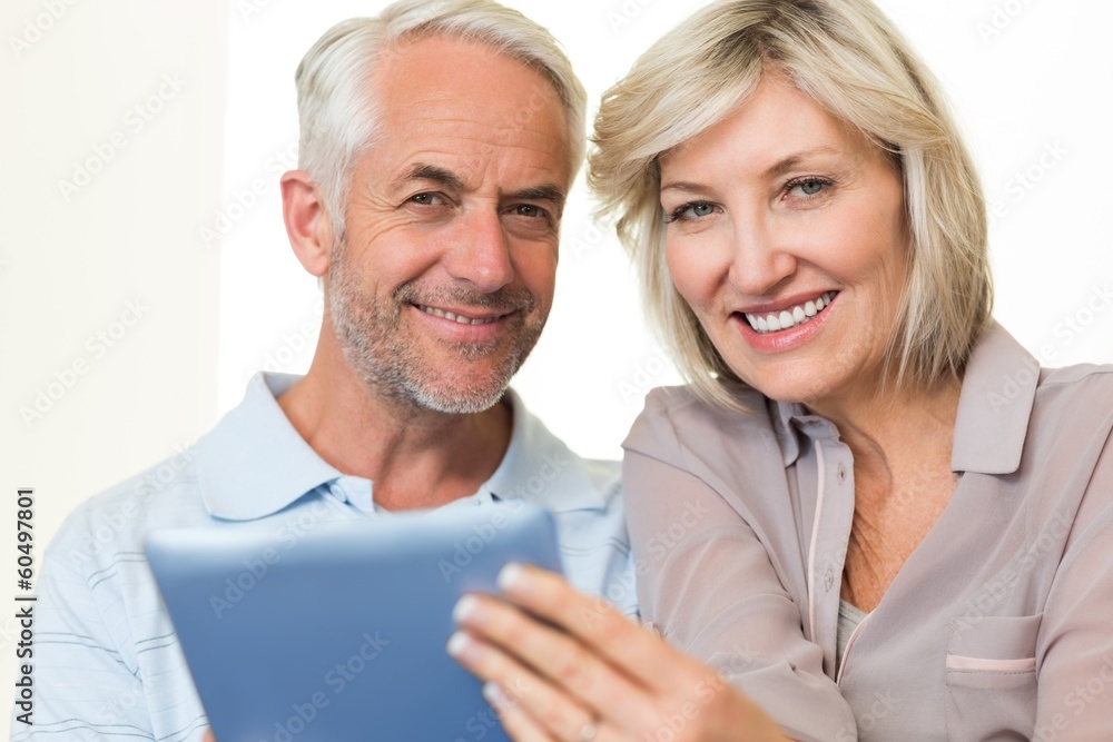 Close-up of a smiling mature couple using digital tablet