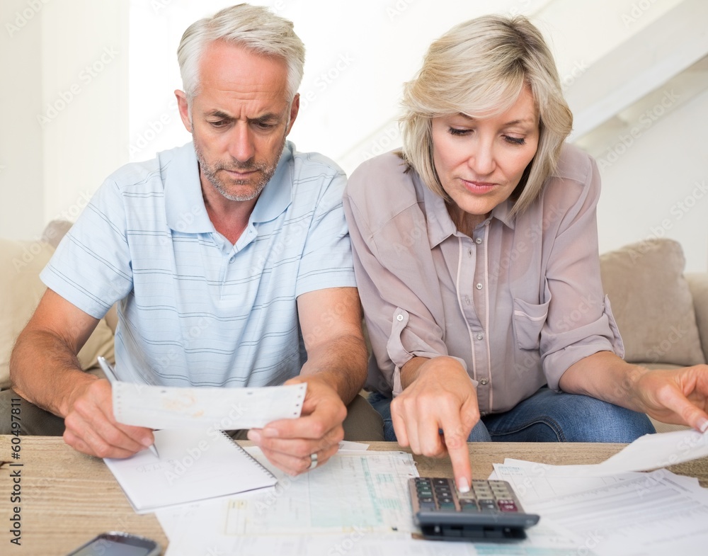 Concentrated mature couple with bills and calculator at home Concentrated mature couple with bills and calculator at home