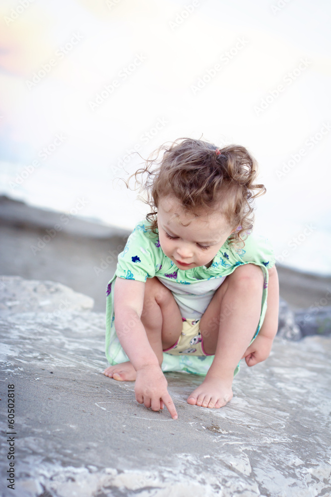 Little girl drawing with finger in the sand Little girl drawing with finger in the sand
