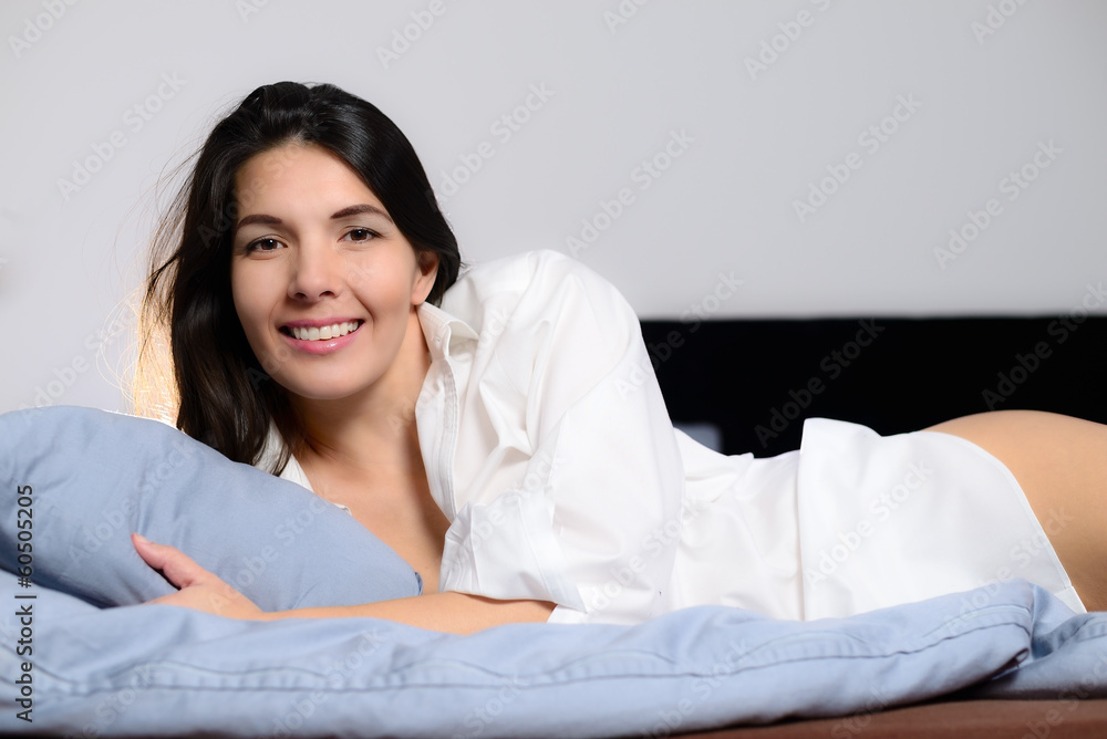 Lachende junge Frau liegt im Bett und genießt den Tag Lachende junge Frau liegt im Bett und genießt den Tag