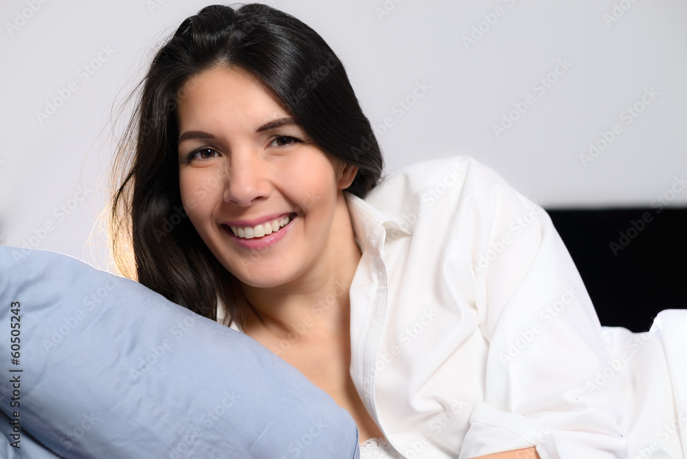 Lachende junge Frau liegt im Bett und genießt den Tag Lachende junge Frau liegt im Bett und genießt den Tag
