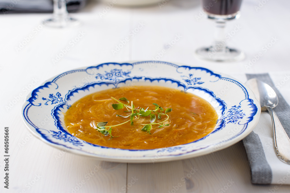 Classic french onion soup on a white wood table with some red wi Classic french onion soup on a white wood table with some red wi