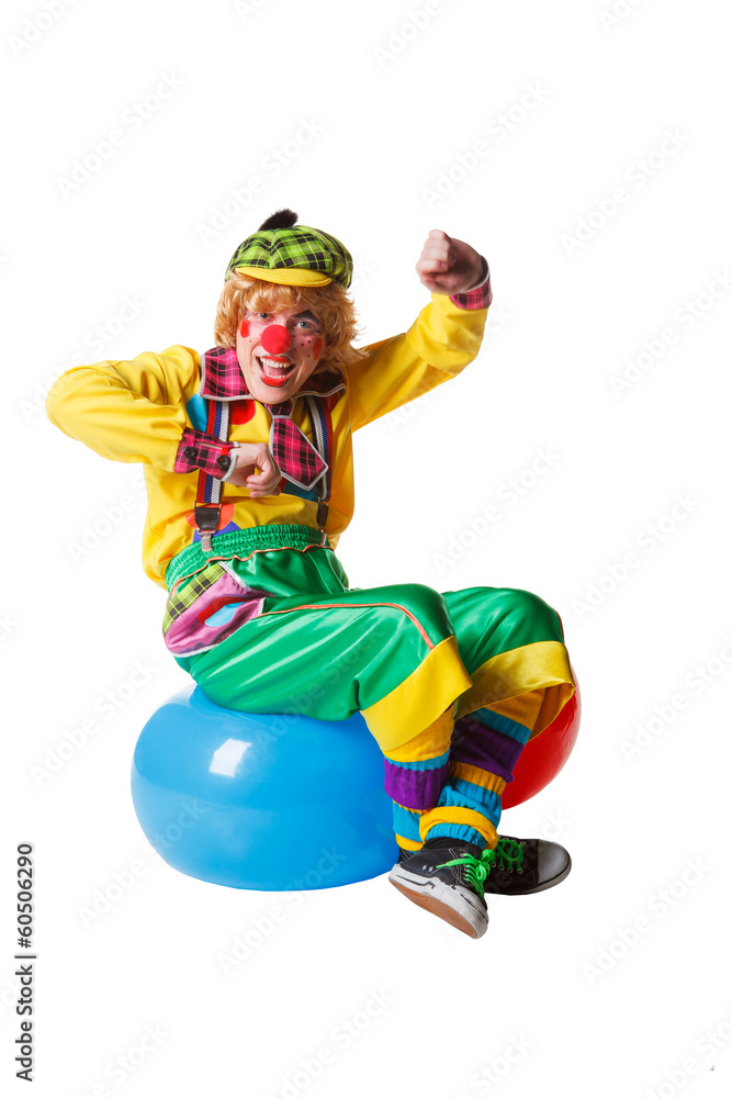 Funny clown sits on blue ball isolated on white background