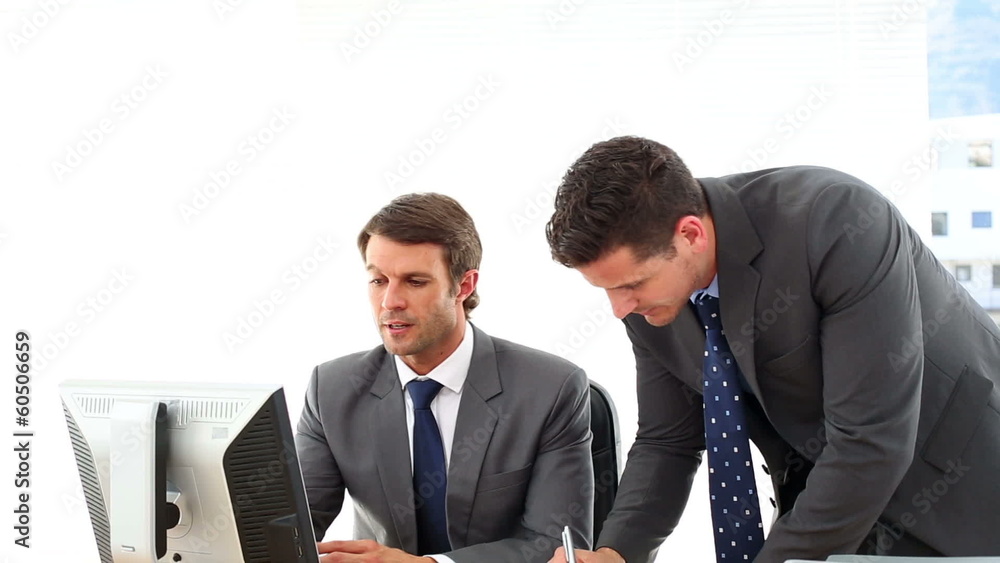 Businessmen looking at computer screen talking Businessmen looking at computer screen talking