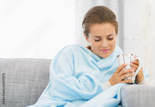 Young woman with flu having cup of hot beverage