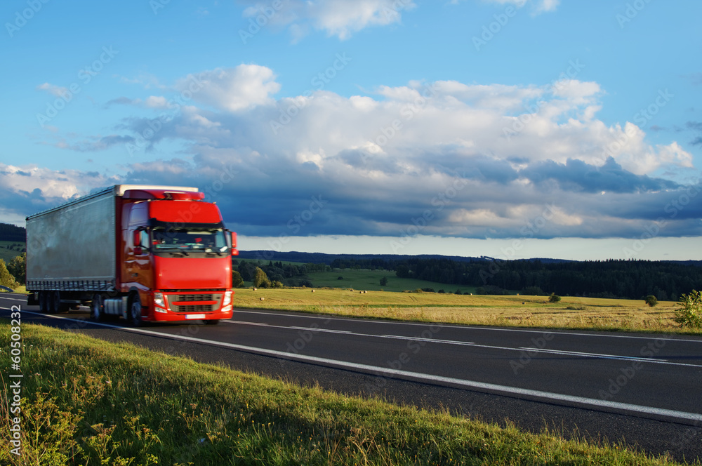 Rural landscape with road and moving red truck