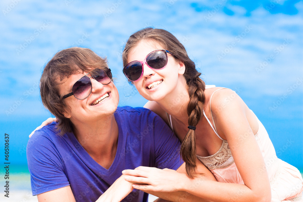 Closeup of happy young couple in sunglasses on beach smiling Closeup of happy young couple in sunglasses on beach smiling