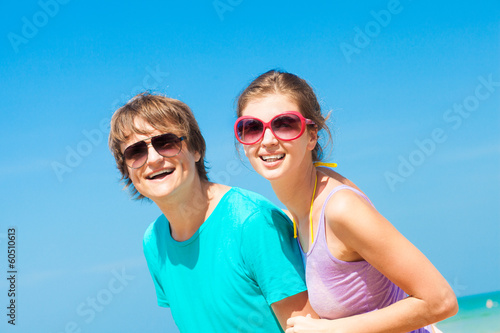 Closeup of happy young couple in sunglasses on beach smiling
