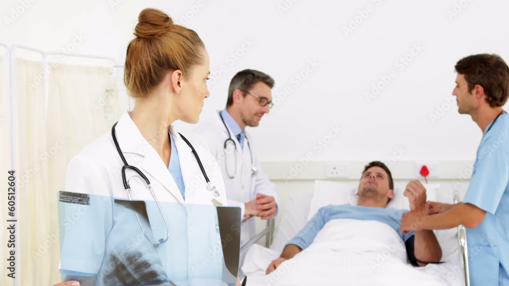 Doctors speaking with patient while one checks xray Doctors speaking with patient while one checks xray