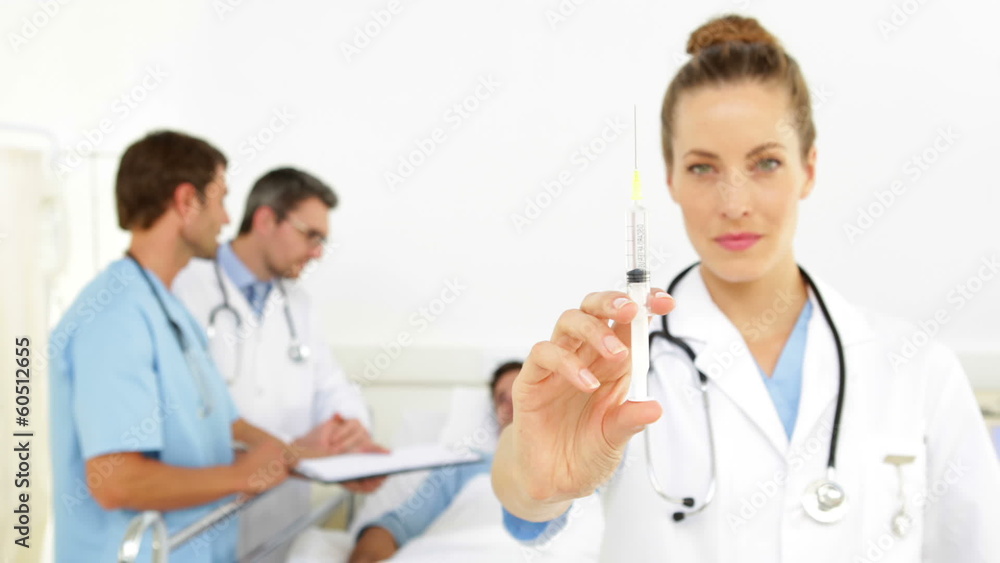 Doctors speaking with sick patient while nurse prepares syringe Doctors speaking with sick patient while nurse prepares syringe