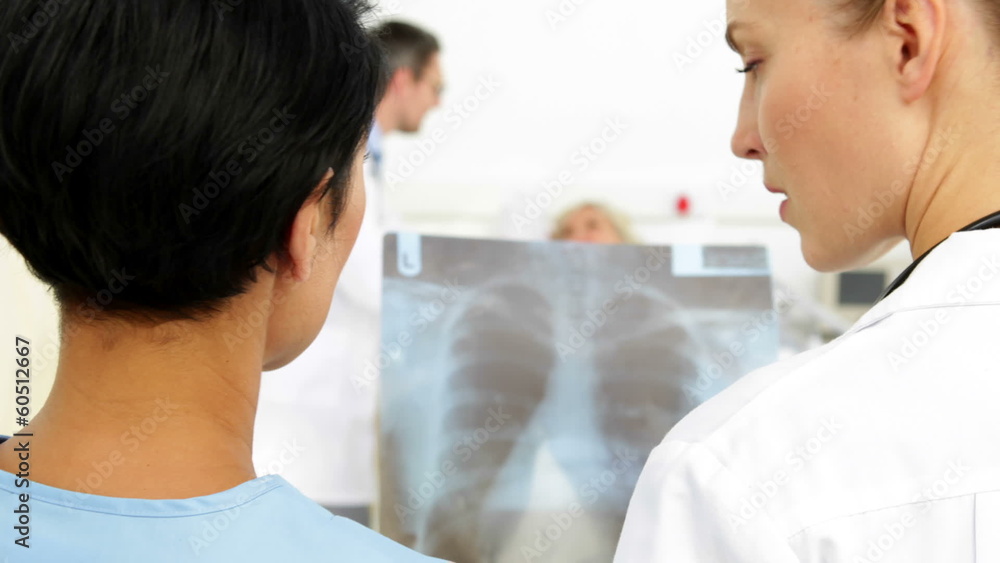 Doctors discussing xray in front of sick patient in bed Doctors discussing xray in front of sick patient in bed