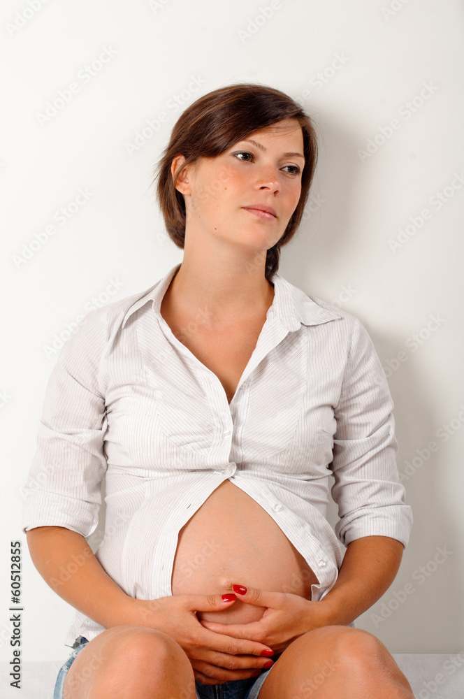 portrait of pretty pregnant brunette on bed about white wall portrait of pretty pregnant brunette on bed about white wall