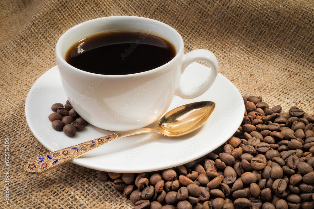 A warm cup of coffee with coffee beans A warm cup of coffee with coffee beans